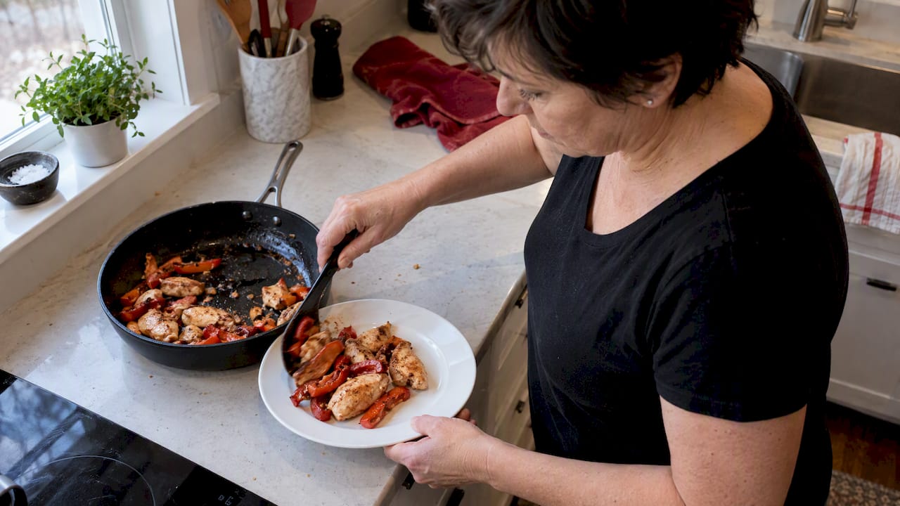 Woman portioning chicken and red peppers