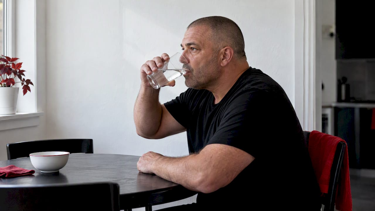 Adult drinking water at a dining table